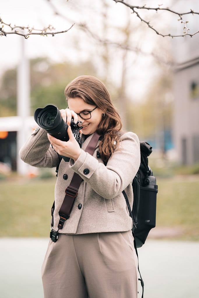 Fotografin hält Kamera in der Hand, sieht in das Display und fotografiert etwas.